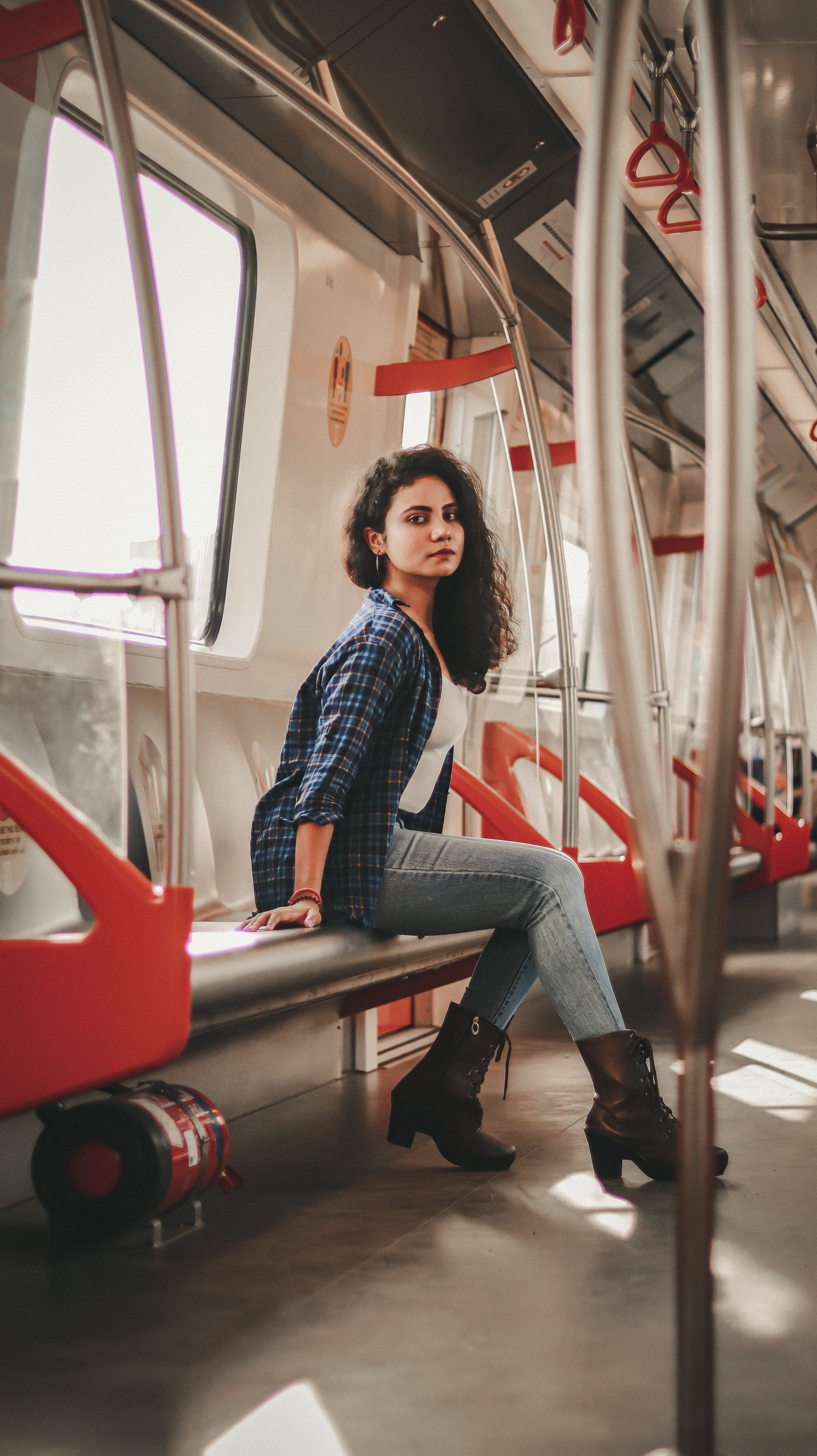 Stylish woman sitting in Ahmedabad metro train, showcasing modern commuter fashion. | Indian Village Development