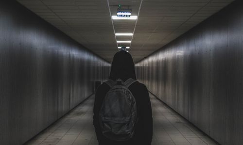 Free A person with a backpack walks through a dimly lit tunnel, conveying mystery and solitude. Stock Photo