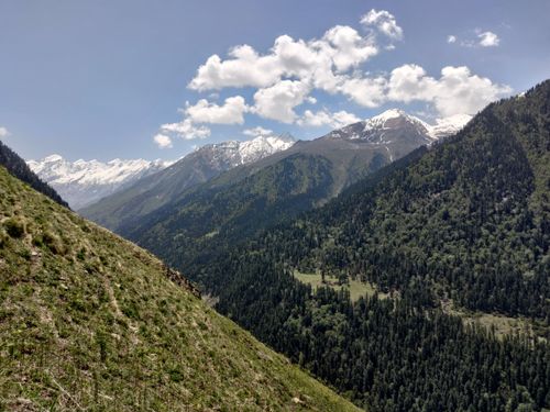 Free Breathtaking view of snow-capped mountains with lush green valleys under a clear blue sky. Stock Photo
