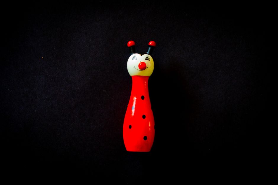 Brightly colored wooden ladybug toy isolated on a dark background, showcasing vivid hues.