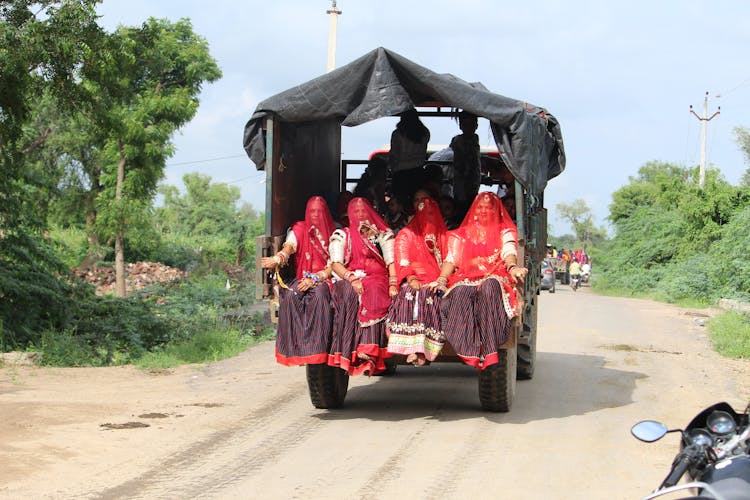 Women Wearing Red Veils Sitting At The Back Of A Truck