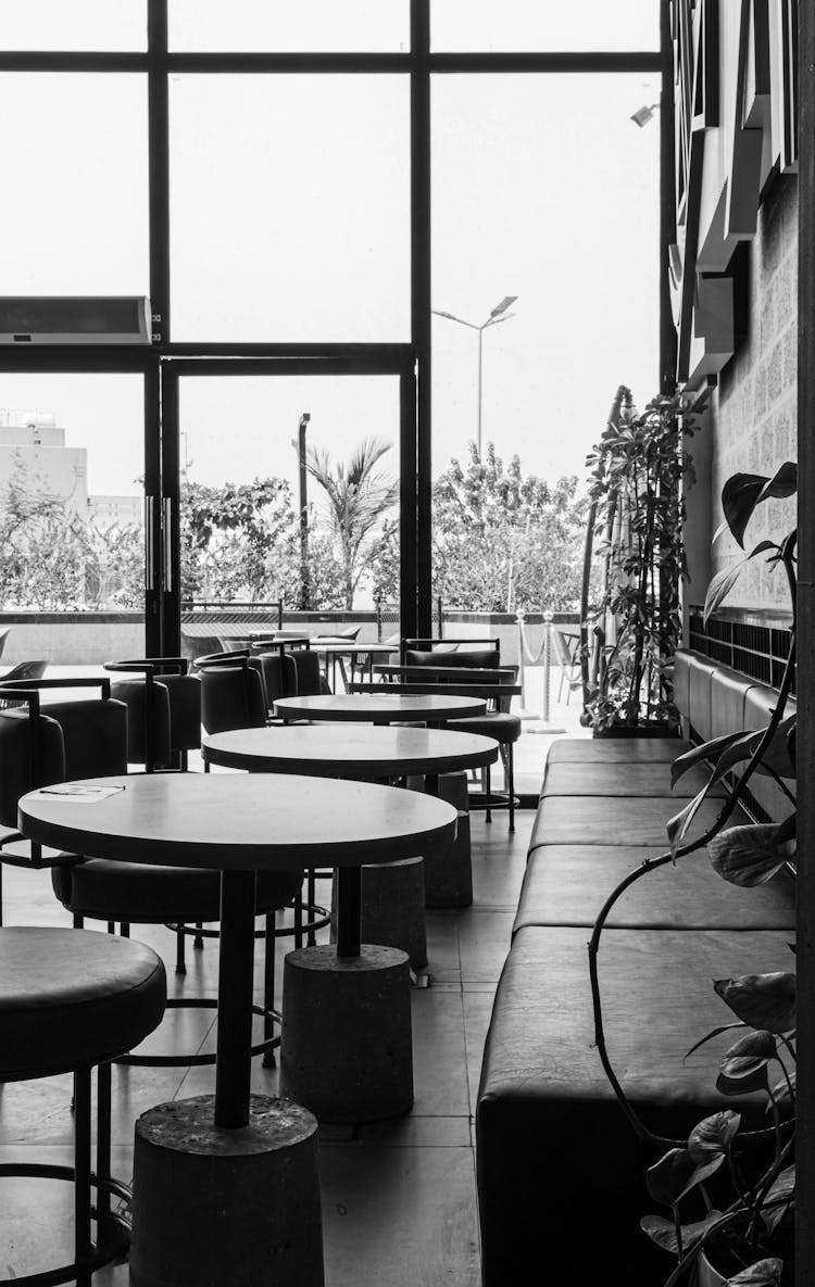 A Grayscale Photo Of Tables And Chairs Inside The Café