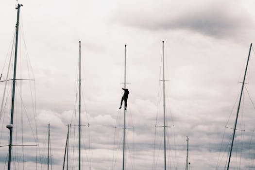 一个大胆的人在戏剧性的多云天空下爬上帆船桅杆，展现了冒险与技巧