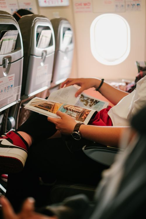 Free Person reading a magazine while seated in an airplane, offering an in-flight experience. Stock Photo