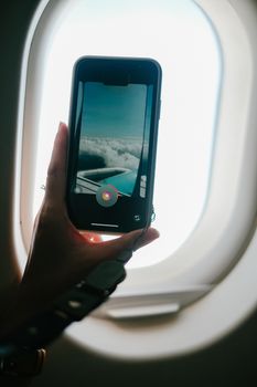 A smartphone captures stunning clouds through an airplane window, showcasing in-flight photography.