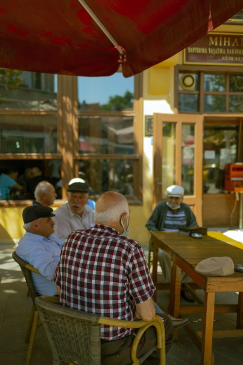 Free Group of senior men sitting outdoors under shade, talking and relaxing. Stock Photo