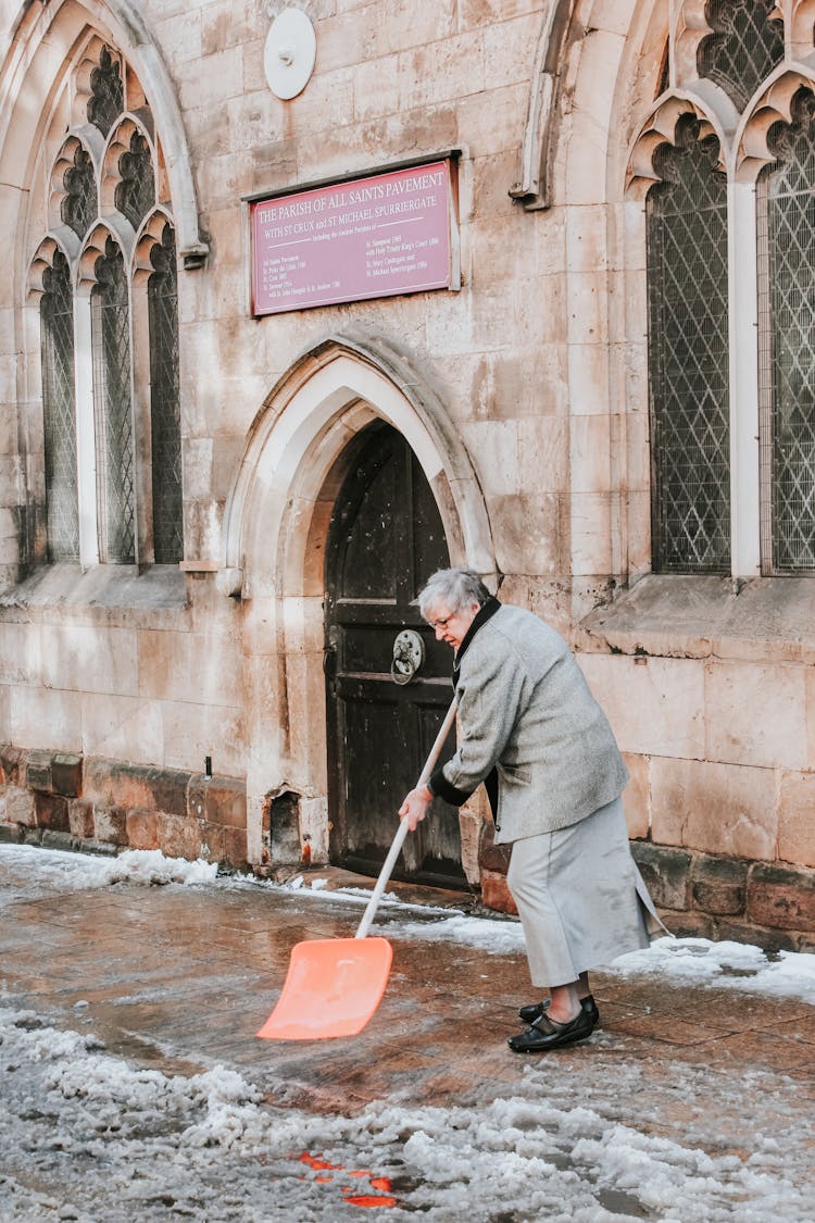 A Woman Plowing The Snow Near The Church