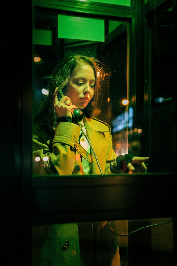 Woman Standing In Phone Booth At Night