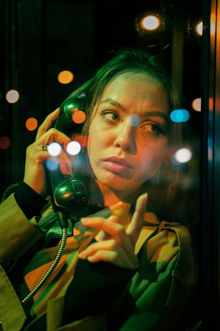 Close-up Of Woman Calling From Phone Booth At Night