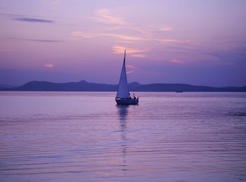 Free A serene sailboat sailing on Lake Balaton during a stunning sunset. Stock Photo