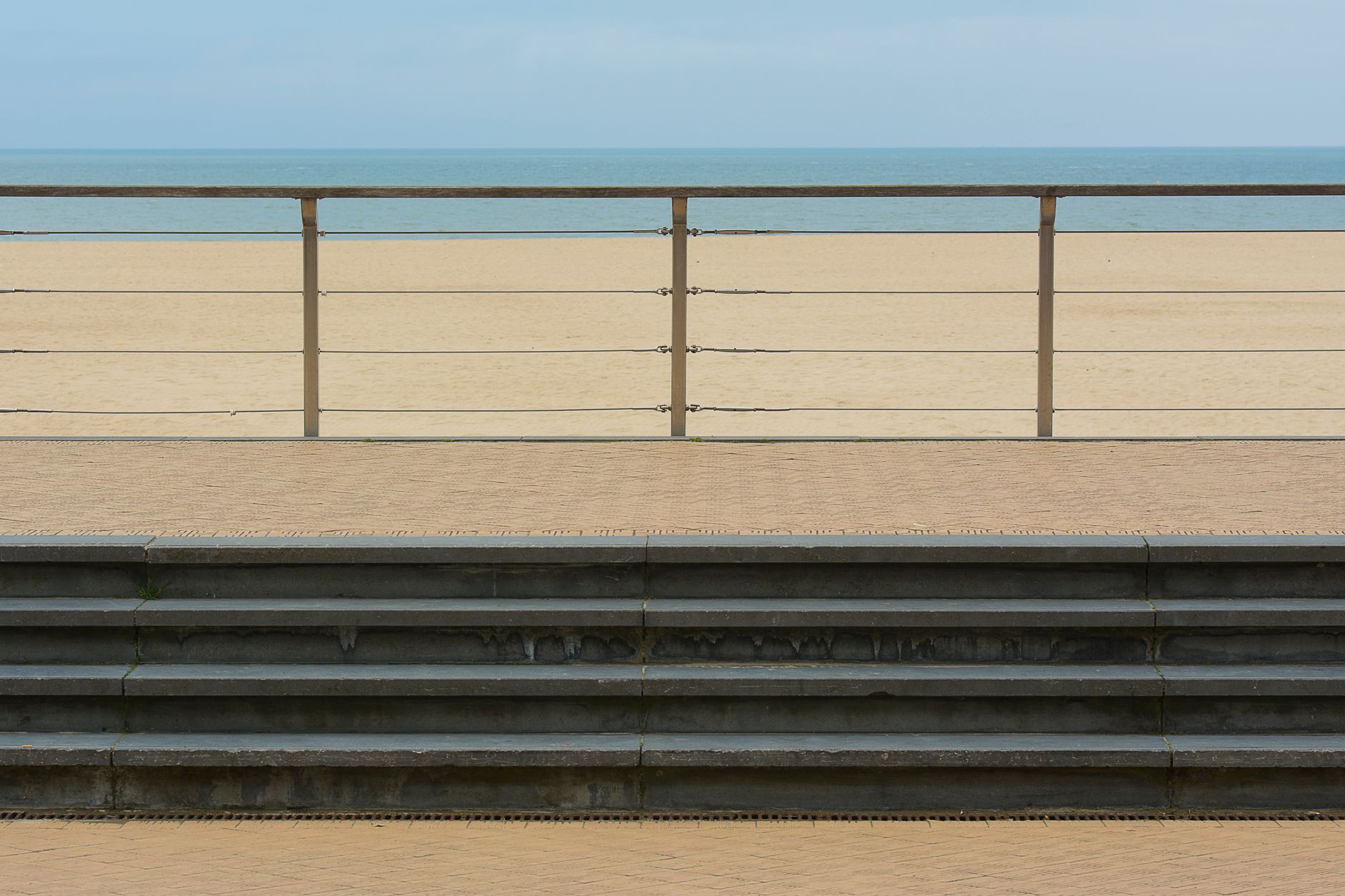 Rail-mounted beach access ramp running from a boardwalk into calm sea