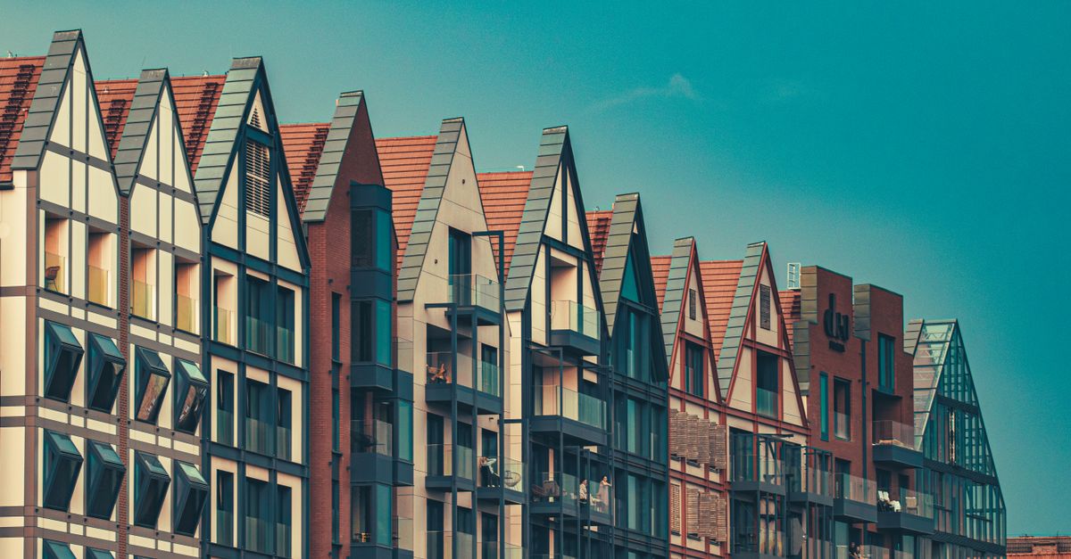 Stylish modern apartment buildings with sharp gabled roofs under a clear blue sky.
