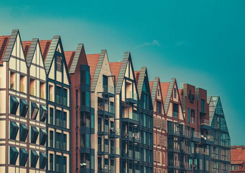 Stylish modern apartment buildings with sharp gabled roofs under a clear blue sky.