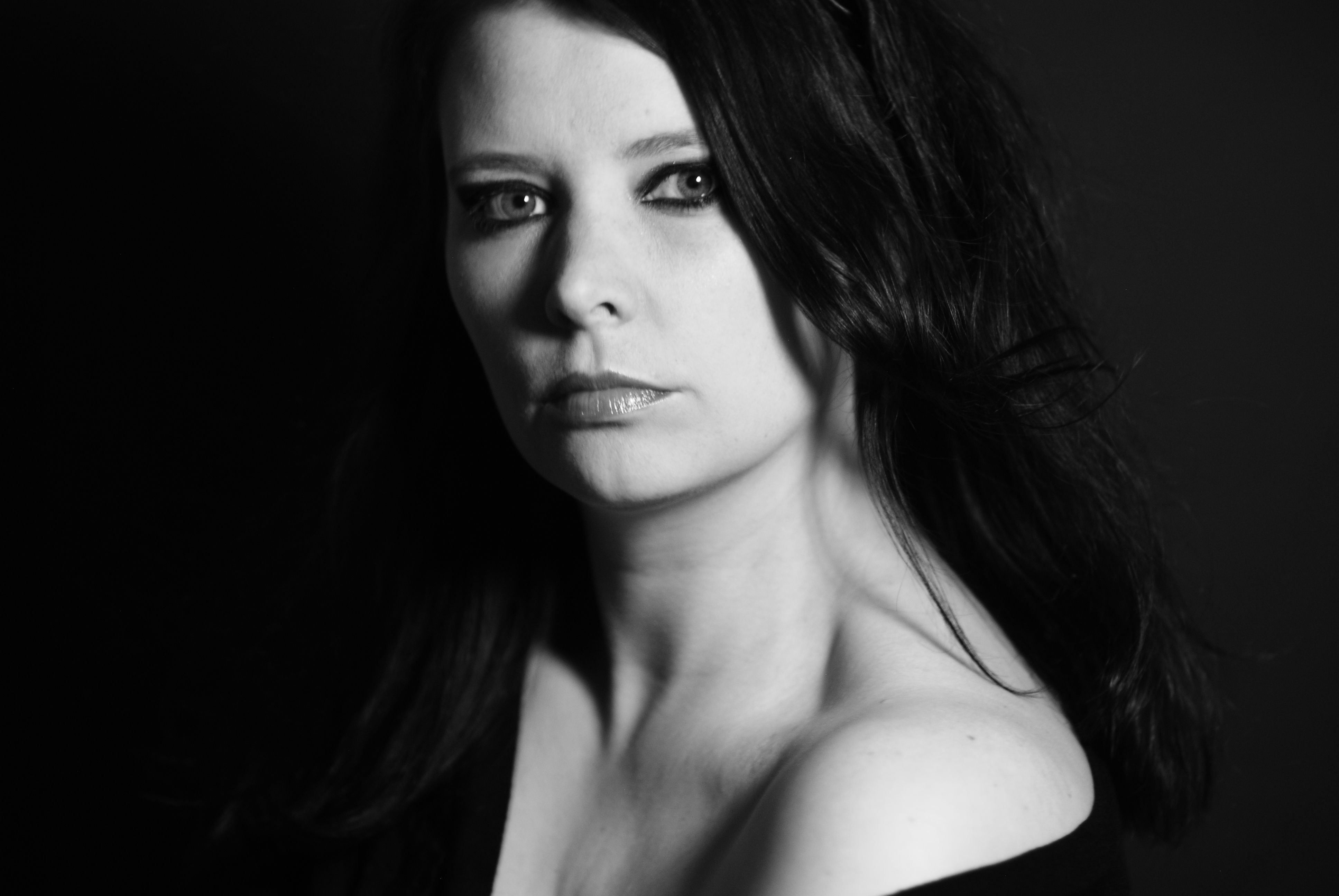 Grayscale portrait of a serious woman with dark hair, highlighting dramatic lighting.