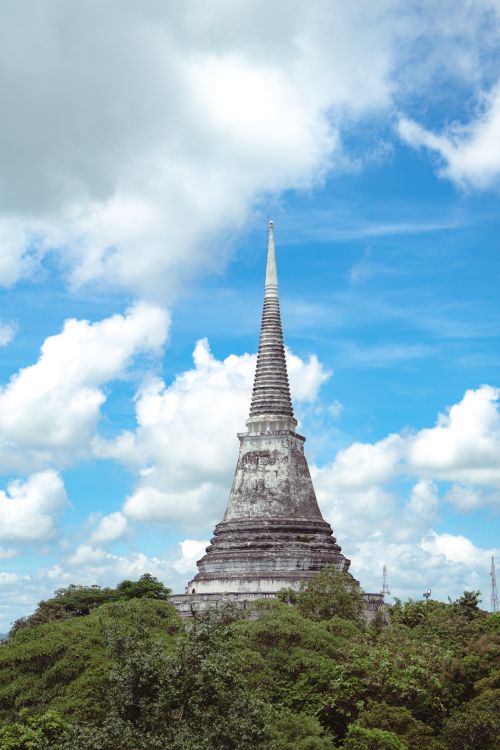 Free Majestic ancient pagoda in Thailand, surrounded by greenery under a vibrant blue sky. Stock Photo