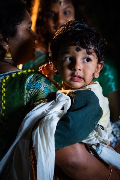 Free A mother lovingly holds her child wearing traditional attire, captured in a warm, intimate moment. Stock Photo