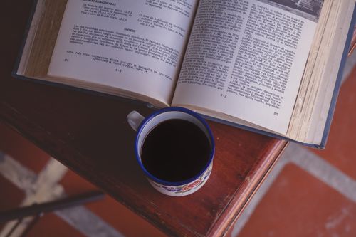 Free An open book and coffee mug on a wooden table, creating a warm, intellectual ambiance. Stock Photo