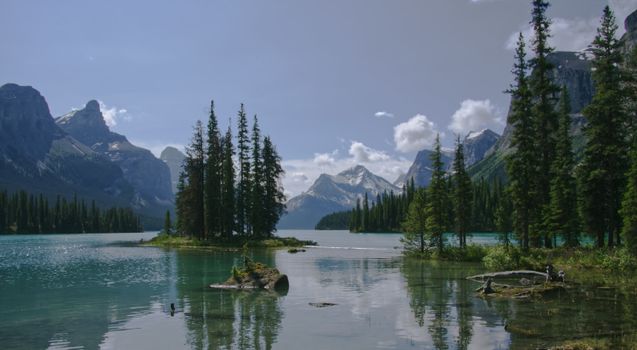 Stunning view of pine trees and mountains reflecting in a tranquil lake in Canada.