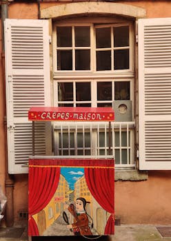 A colorful crepes cart in front of a traditional Lyon window.