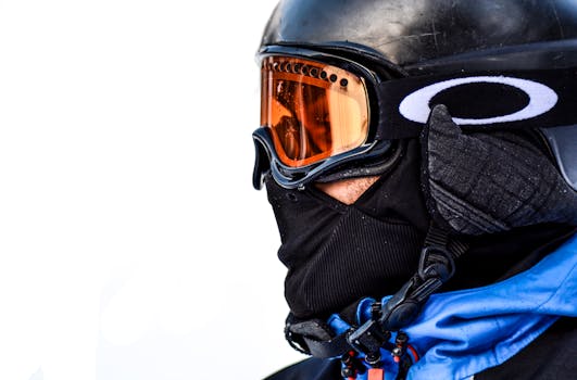 Close-up view of a skier wearing protective winter gear with goggles, set against a white background.