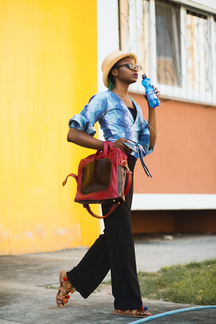 Woman In Blue Top Holding Blue Bottle And Red 2-way Bag Outdoors