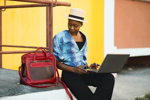 Woman Sitting Beside Bag And Using Laptop