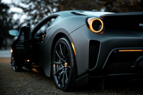 Free Detailed close-up shot of a luxury sports car's wheel and taillight with blurred background. Stock Photo