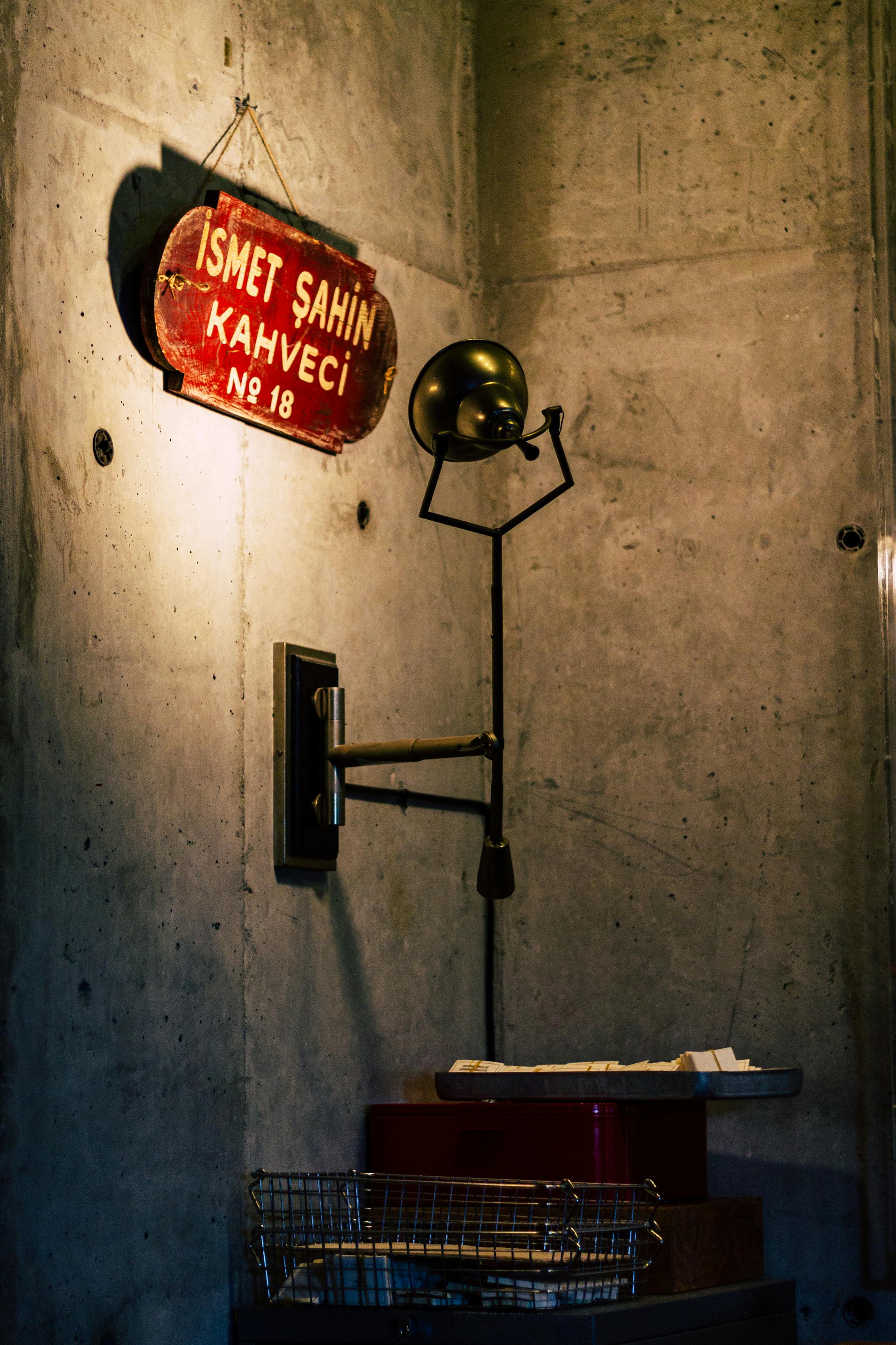 A vintage wall lamp with an antique sign in a dimly lit Istanbul café corner.
