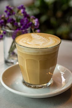 Close-up of a beautifully crafted latte with fern latte art, perfect for a cozy café atmosphere.