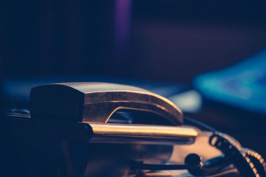 A classic office telephone handset in a moody, dimly lit setting.