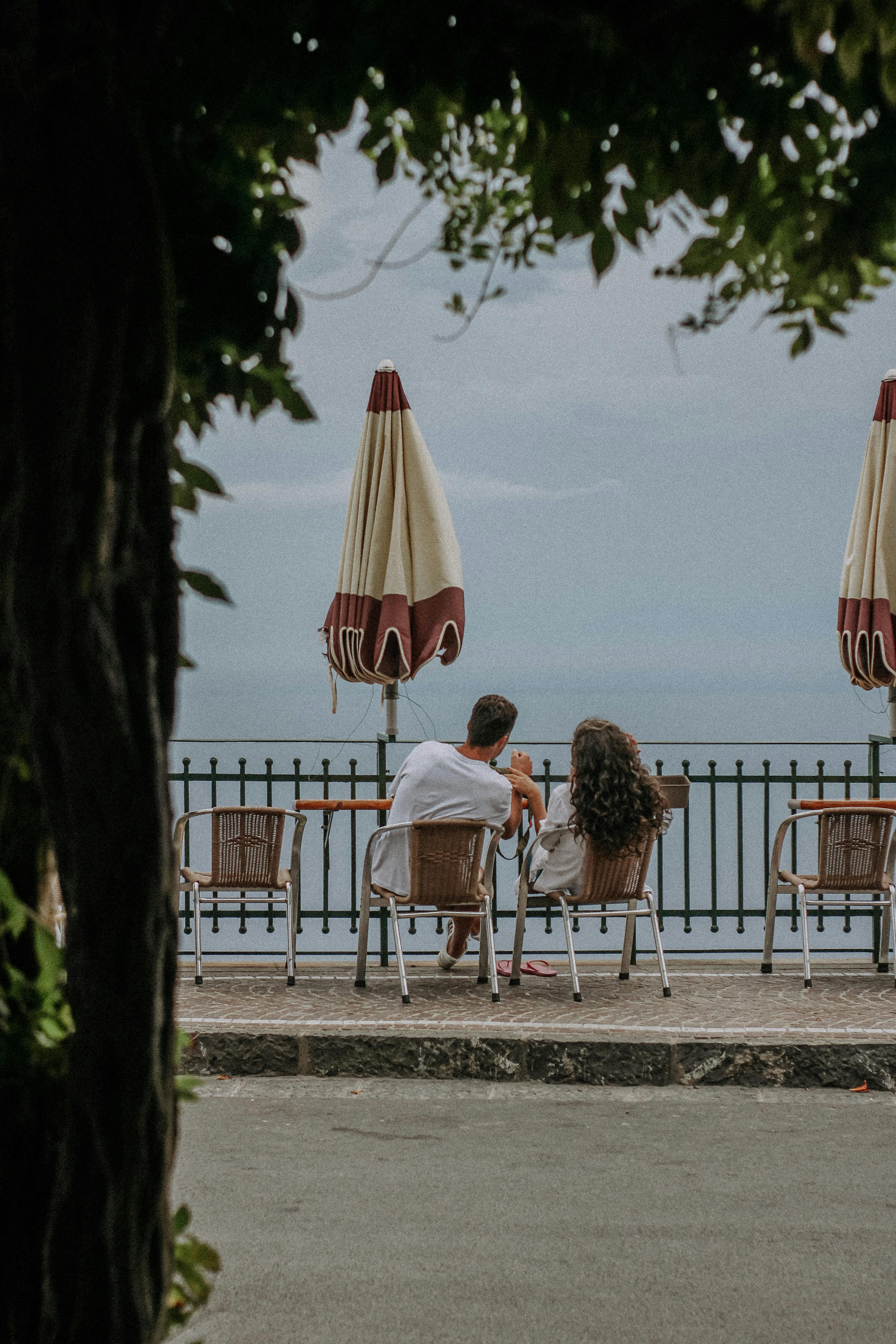 A couple sitting and talking on a terrace overlooking the sea, creating a romantic atmosphere.