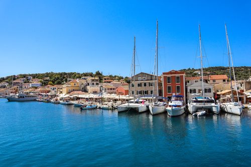 Free Explore the vibrant harbor of Gaios, Greece, featuring docked yachts, colorful buildings, and clear blue skies. Stock Photo