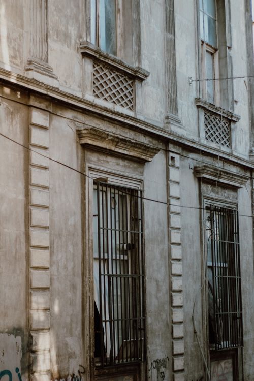 Free A vintage building facade with metal bars and intricate design elements in a city setting. Stock Photo