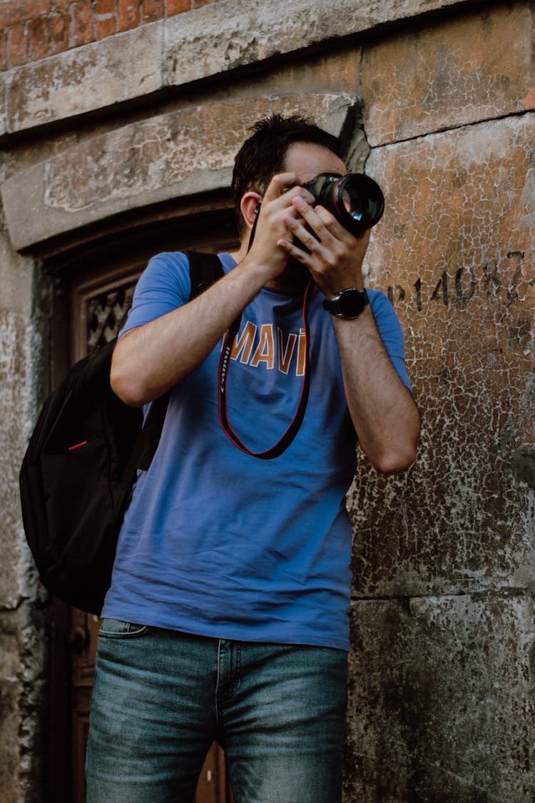 Man In Blue Shirt Taking Pictures With A Camera