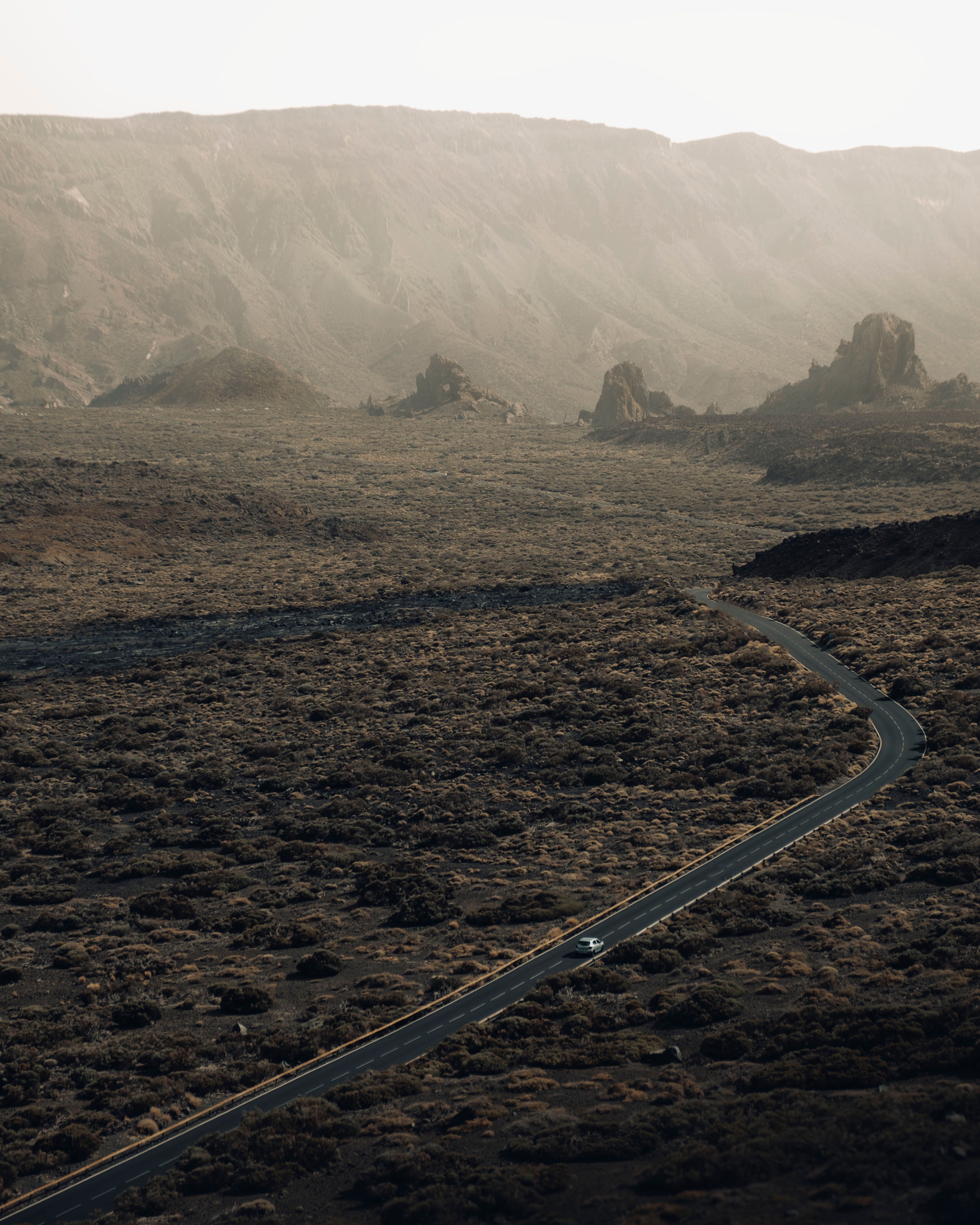 Aerial shot of a winding road amidst rugged mountain terrain, capturing natural beauty.