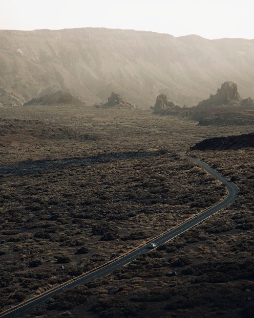Aerial shot of a winding road amidst rugged mountain terrain, capturing natural beauty.