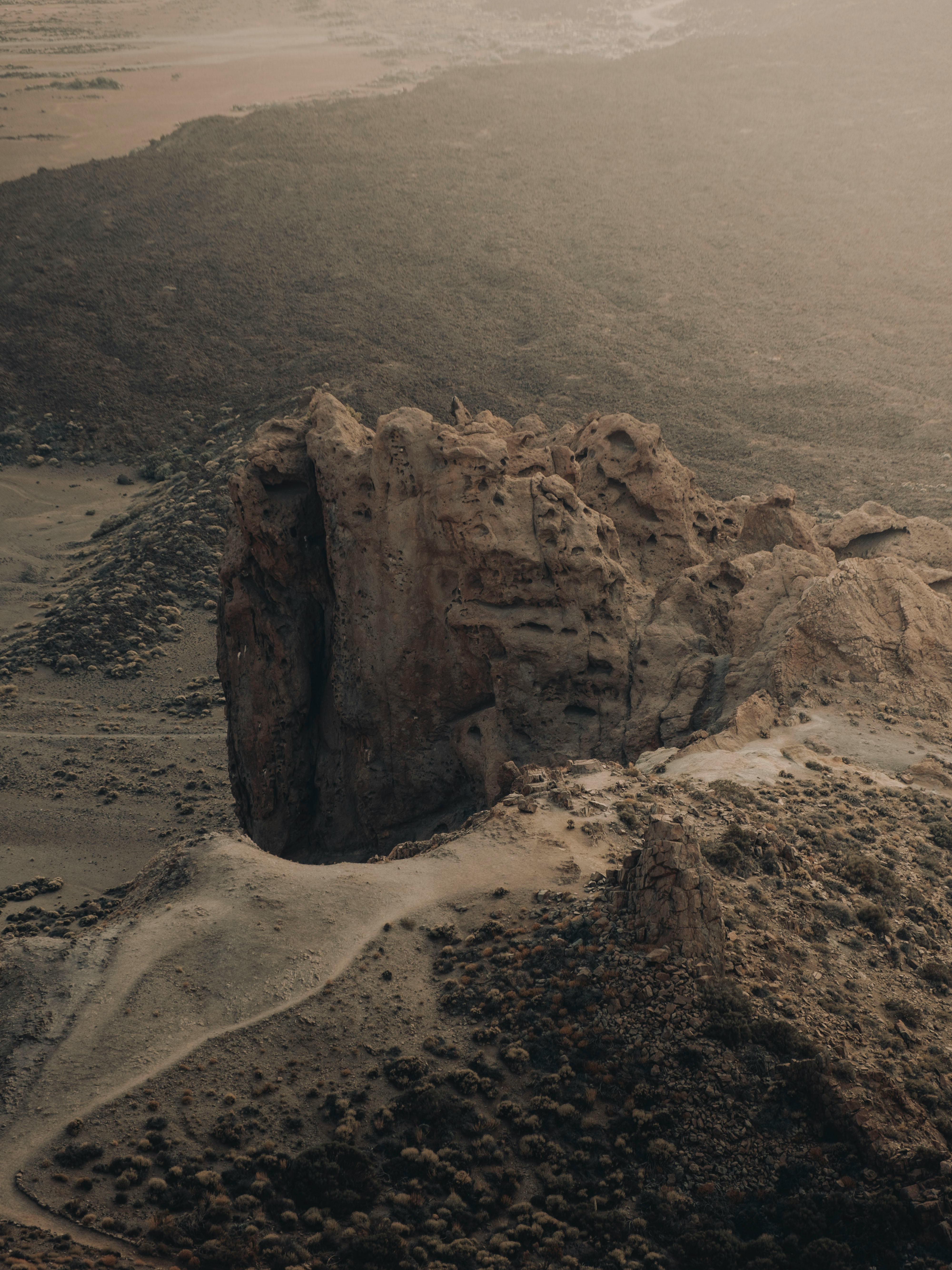 Aerial photograph capturing a dramatic rock formation in a desert landscape at sunset.