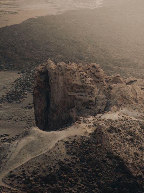 Aerial photograph capturing a dramatic rock formation in a desert landscape at sunset.