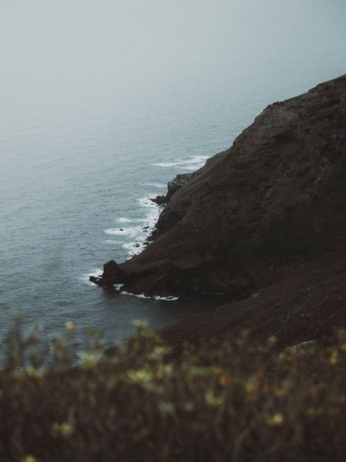 Free A steep cliff descending into the ocean under a cloudy sky, conveying tranquility. Stock Photo