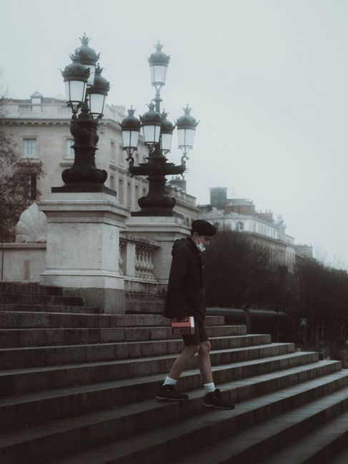 A man walks down stone steps amidst foggy city architecture, capturing a moody winter atmosphere.