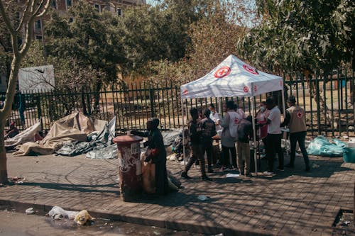 Red Cross Stall on Street Covered in Rubbish