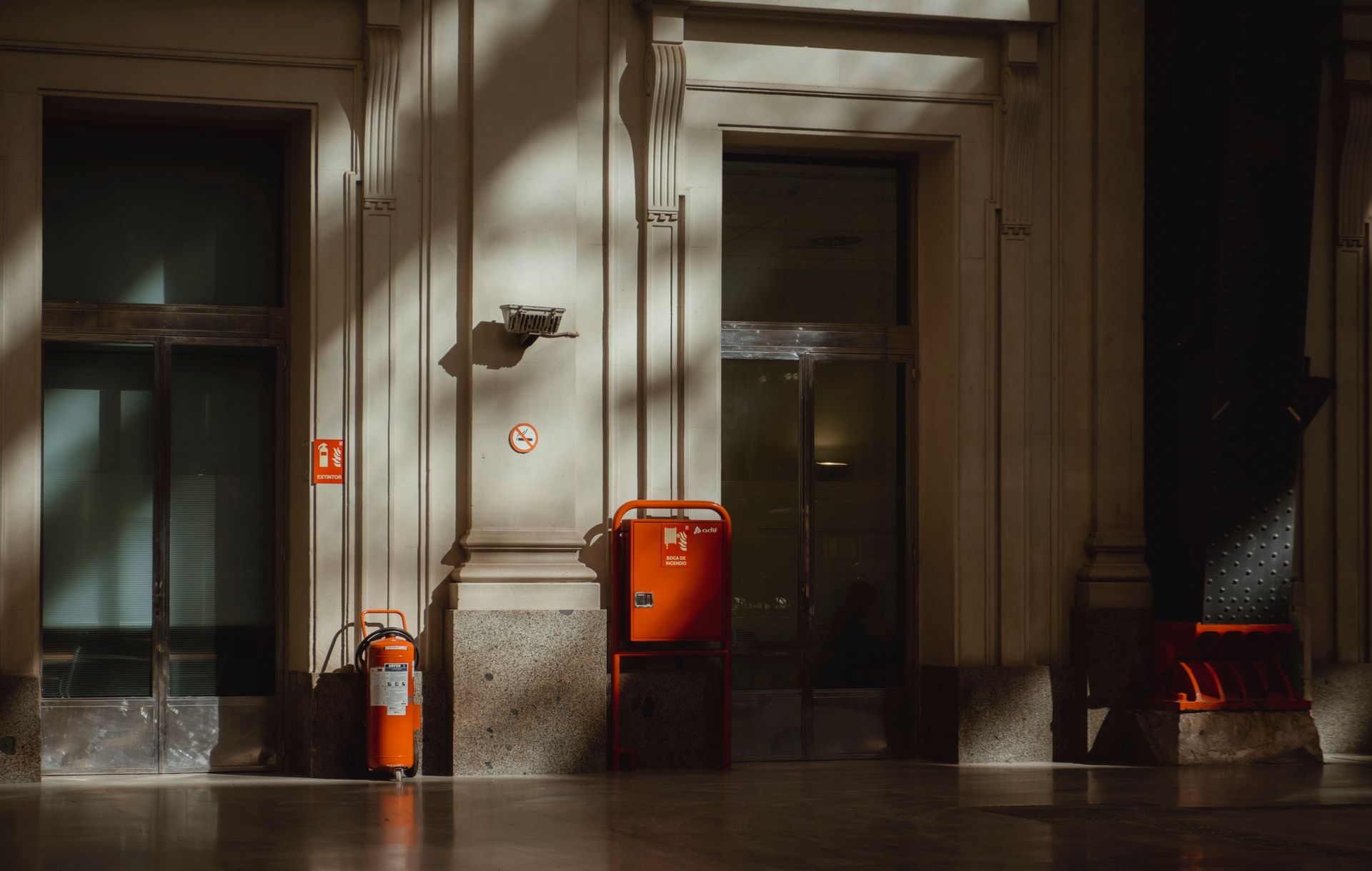 Interior scene featuring a fire extinguisher and dramatic light and shadows on the wall.