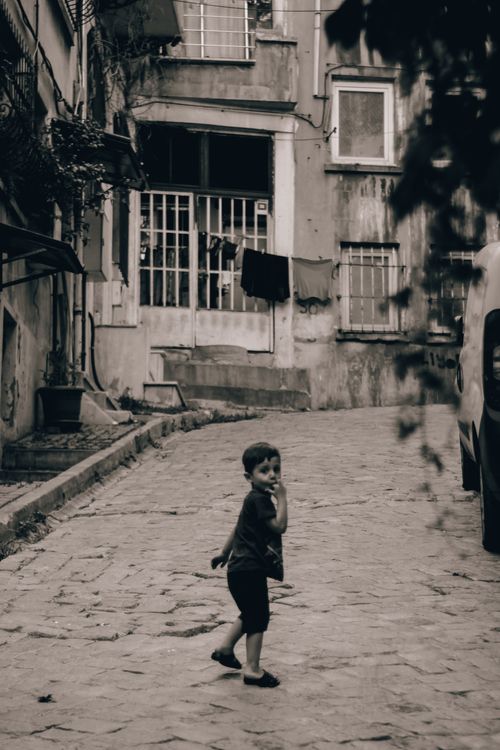 Free Black and white photo of a young boy in a deserted urban street setting. Stock Photo