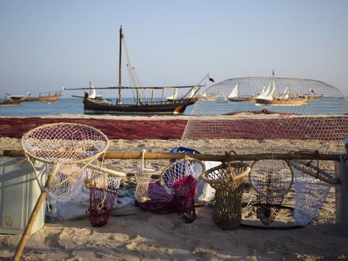 Free Traditional fishing scene with nets and dhows on a sunny Doha beach. Stock Photo