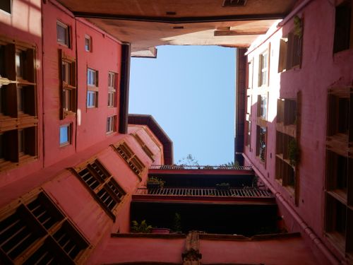 Free A distinctive Lyon courtyard with vibrant hues and a clear blue sky, showcasing French architecture. Stock Photo