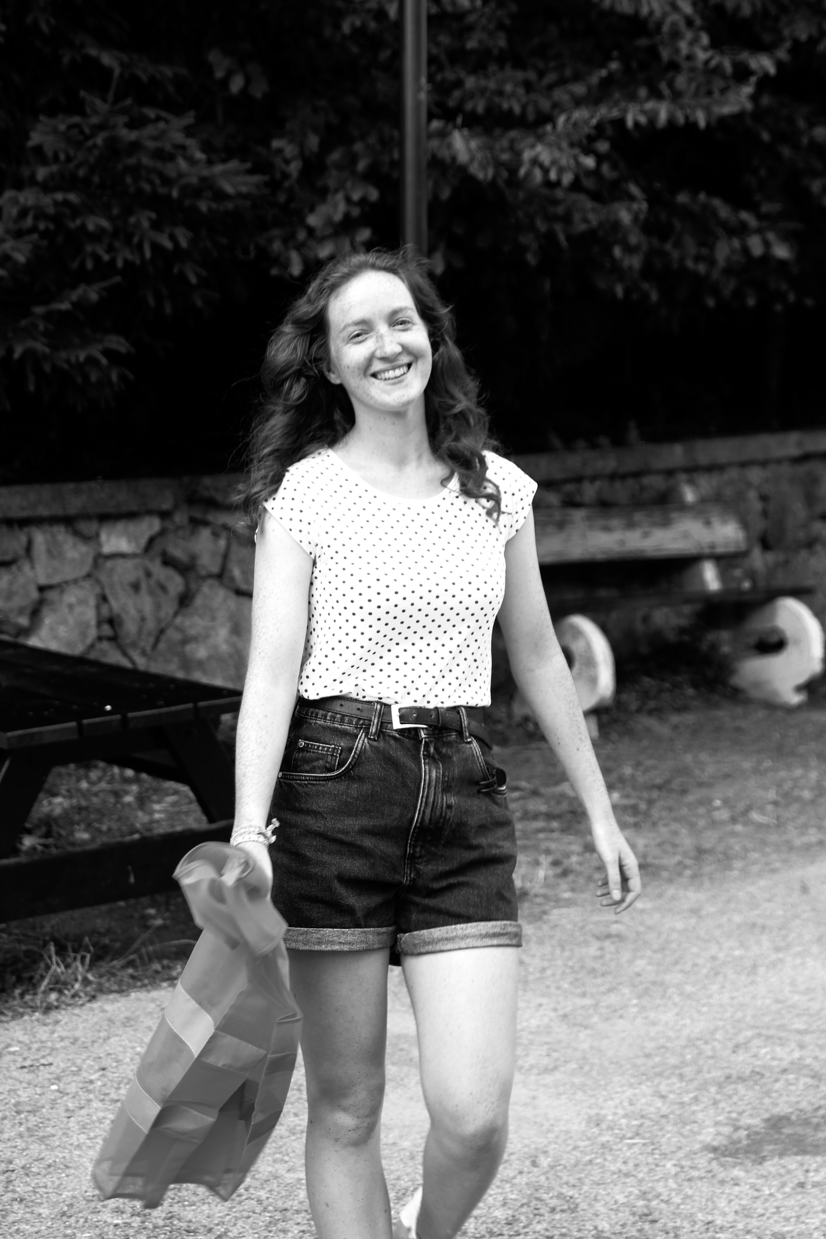 Happy woman walks with a plastic bag, smiling on a sunny day.