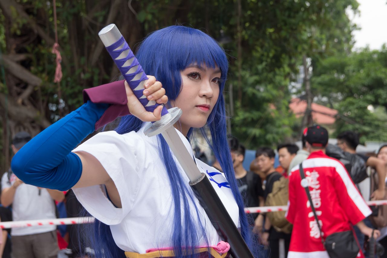 cosplay participant dressed as a character holding a sword at an outdo