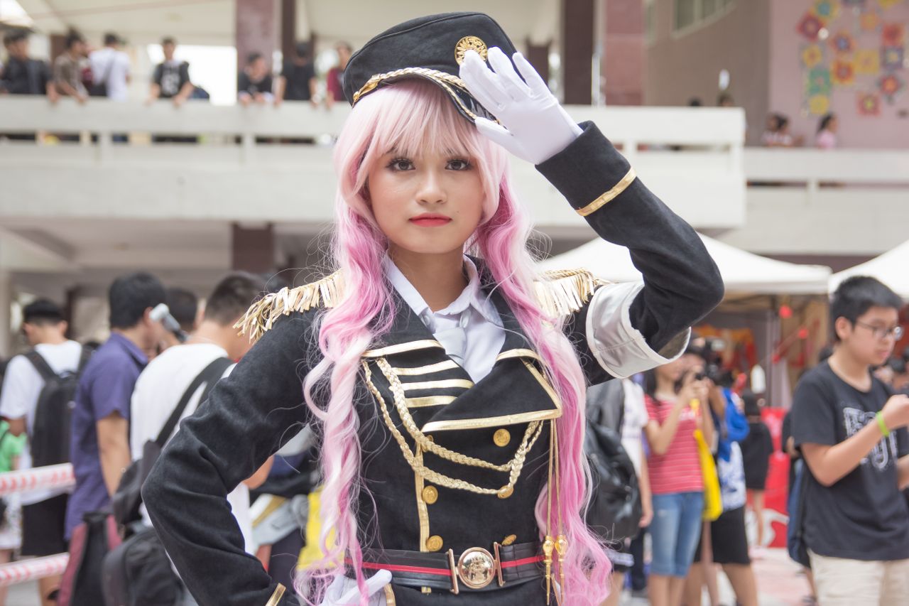 young woman in detailed cosplay outfit saluting at an indoor event