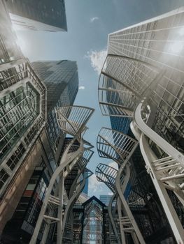 Low angle view of modern skyscrapers and artistic structures in an urban environment.