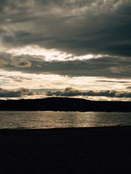 A peaceful lake reflecting the cloudy sky during twilight, creating a serene atmosphere.